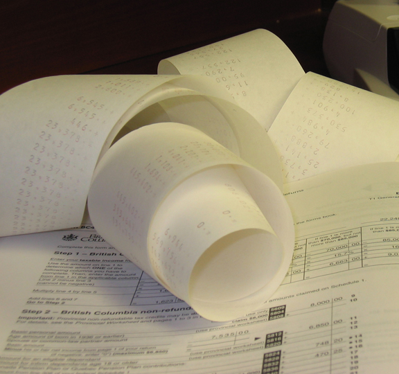This image shows rolled-up calculations on paper from a printer calulator, set on top of a tax guide for British Columbia page.