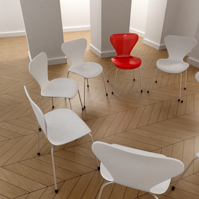 A circle of white chairs with one red chair